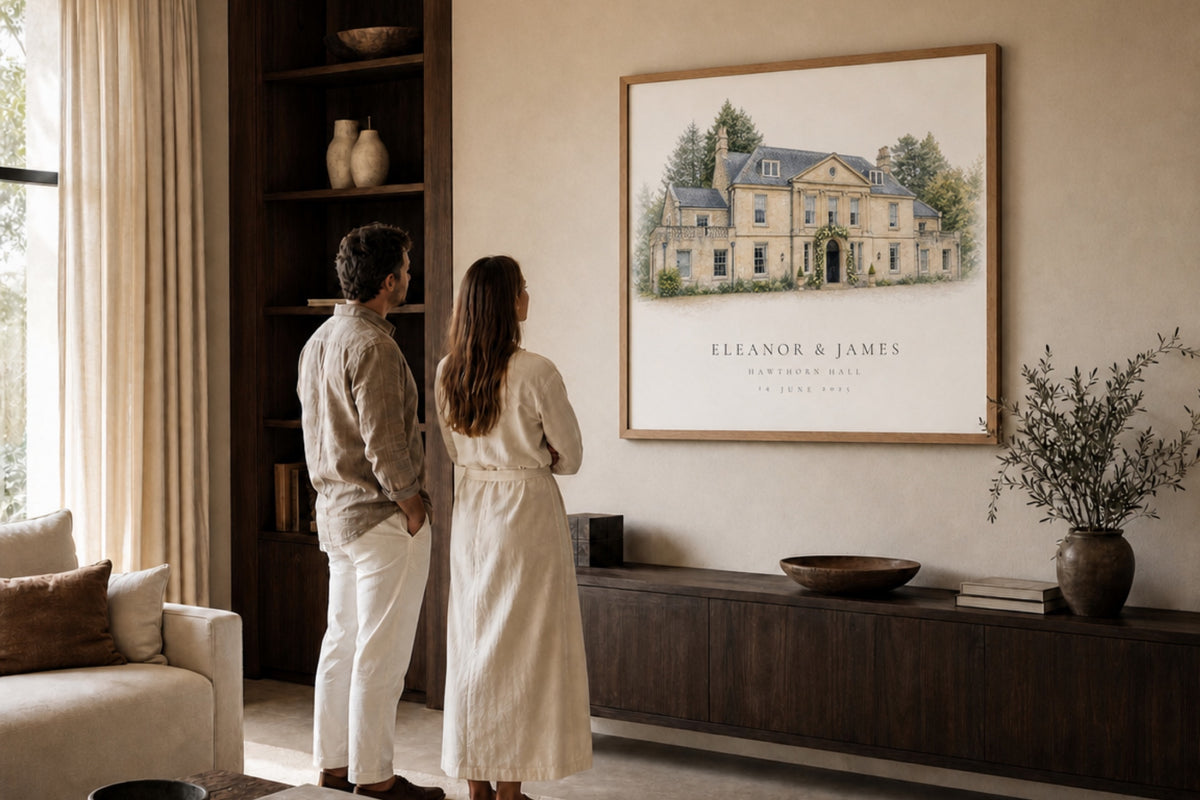 A couple looking at a personalised wedding-venue portrait displayed above a sideboard.