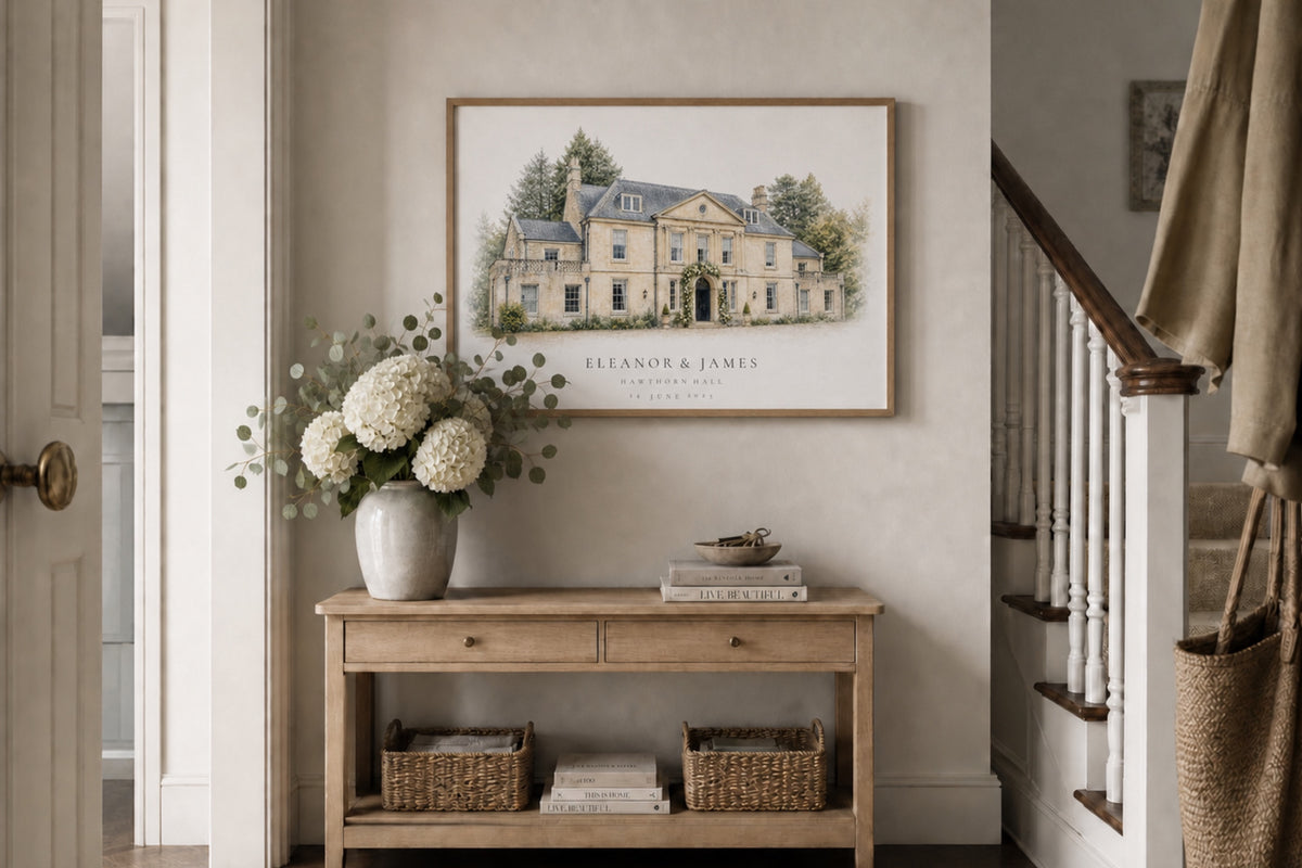 A personalised wedding-venue portrait above a wooden console beside white hydrangeas.